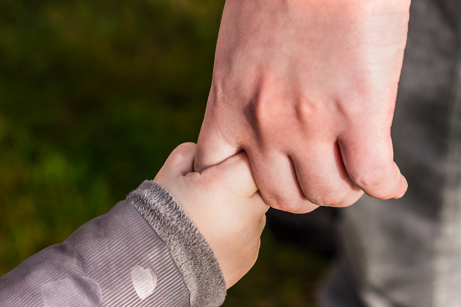Closeup of a child and adult holding hands